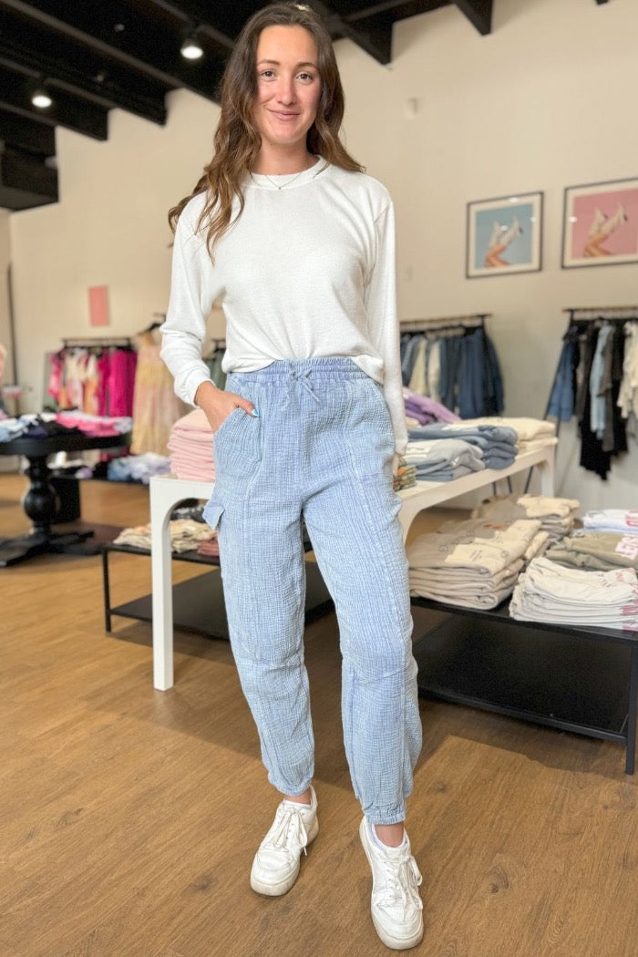 gauzy crinkle material cargo pants in denim blue color with elastic and drawstring waist, side and leg pockets, and elastic cuffs at ankle