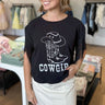 black crop graphic t-shirt, with a cowboy boot and hat design printed on the front with the words Cowgirl in distressed lettering, embellished with fringe detail on the shoulders