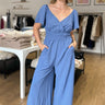 blue surplice flowy wide leg jumpsuit with elastic waist and v-neck with snap closure, flowy sleeves and side pockets