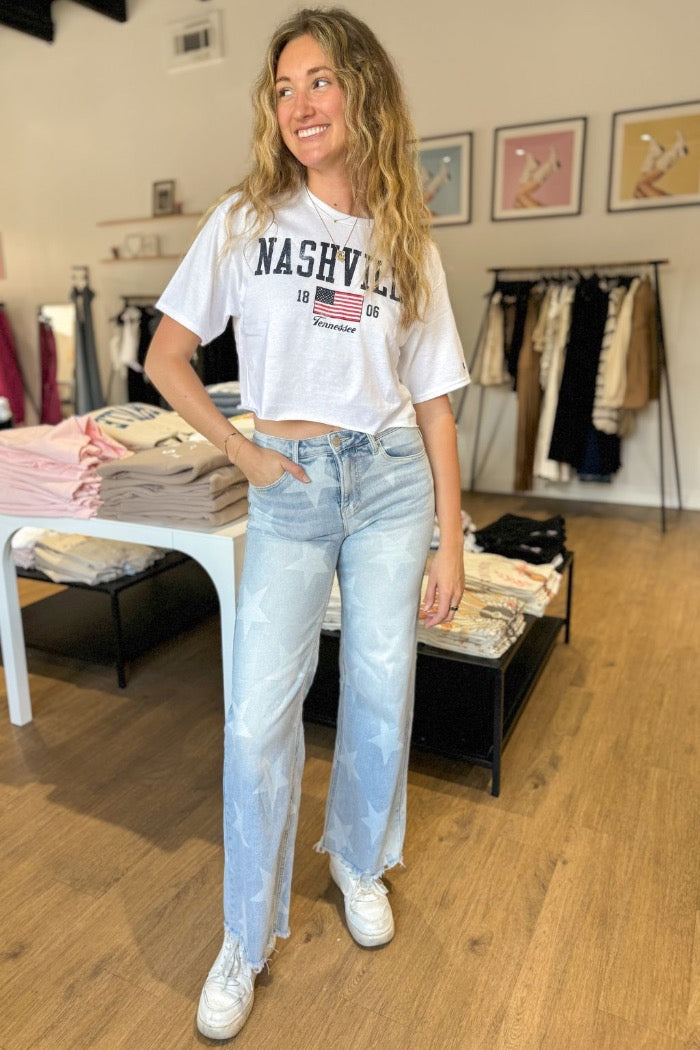 light wash denim wide leg jeans with lighter star print design throughout, with zipper fly and button closure, front and back pockets and raw distressed hem