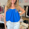 bubble hem spaghetti strap tank top blouse with adjustable straps, cropped length that hits at waistline, and v-neck design in a bright hue of blue